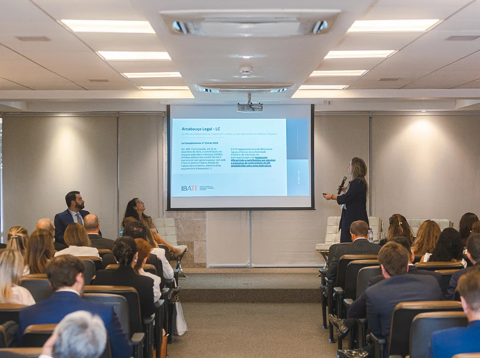 Aula do IBATT em auditório, com participantes assistindo a apresentação sobre arcabouço legal da transação tributária